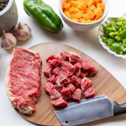 A variety of fresh ingredients including beef, vegetables, and seasonings ready for a homemade stew.