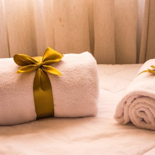 Luxurious white towels adorned with golden ribbons on a bed, creating an elegant and welcoming atmosphere.