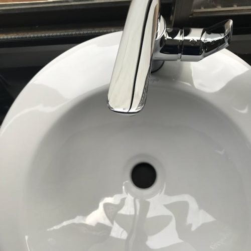 Close-up image of a modern stainless steel faucet and ceramic sink, highlighting cleanliness and hygiene.