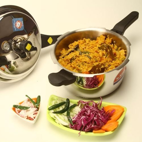 Delicious Indian biryani in a pressure cooker, garnished with fresh vegetables and spices, showcasing rich culinary traditions.