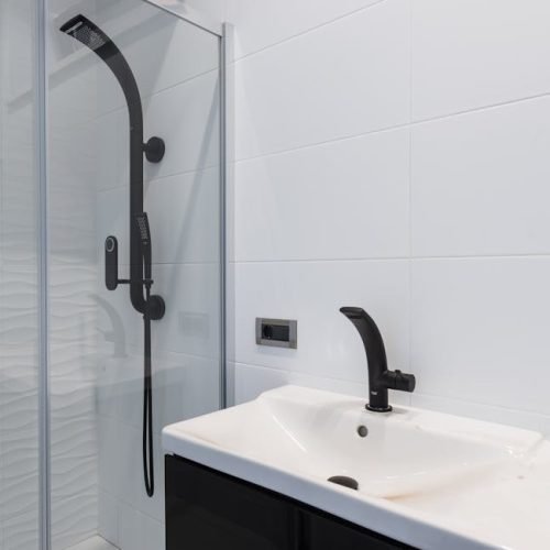 Minimalist bathroom featuring black sink and shower fixtures with white tiles.